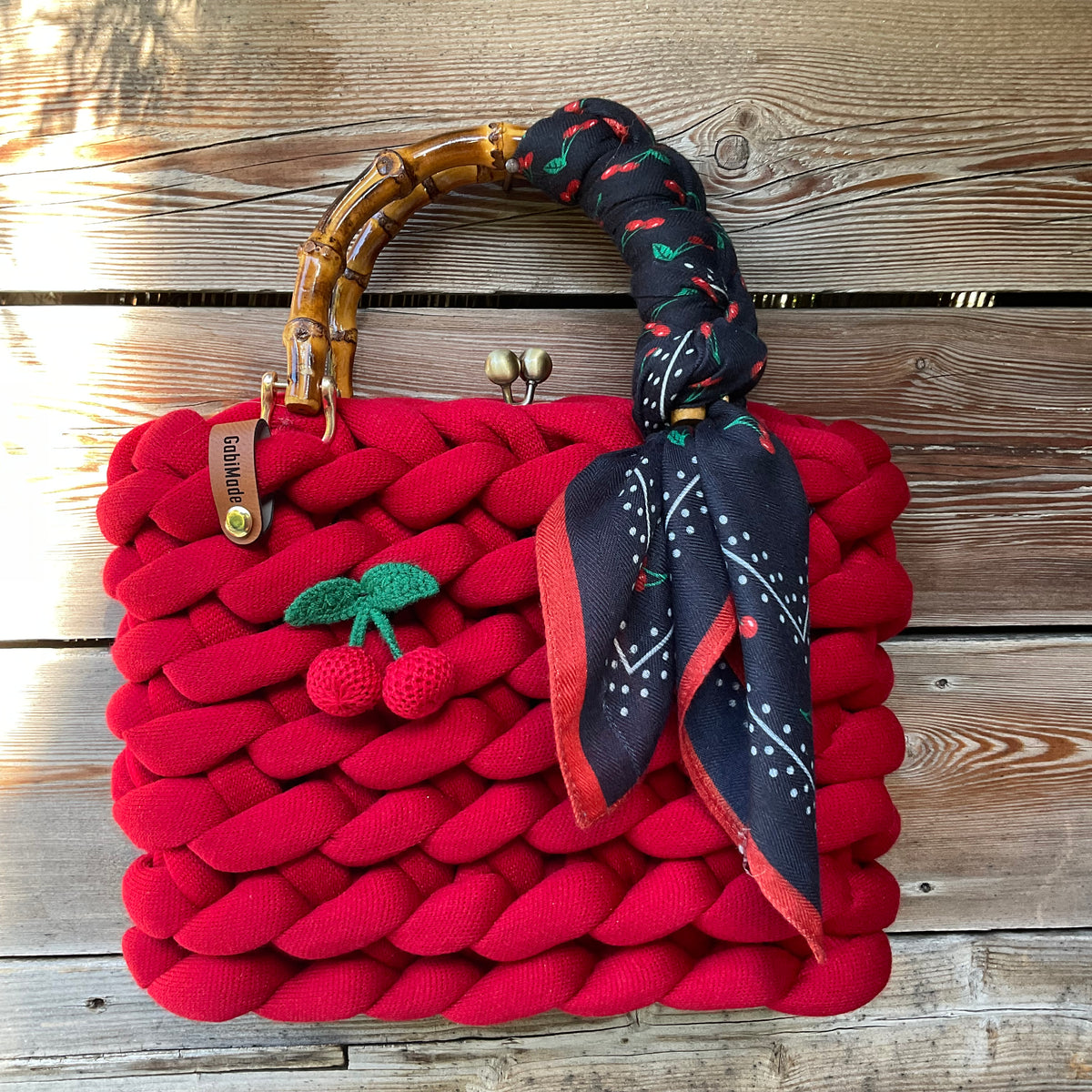 Eine gestrickte rote Trachtentasche mit Kirsche und Bambusgriffen 