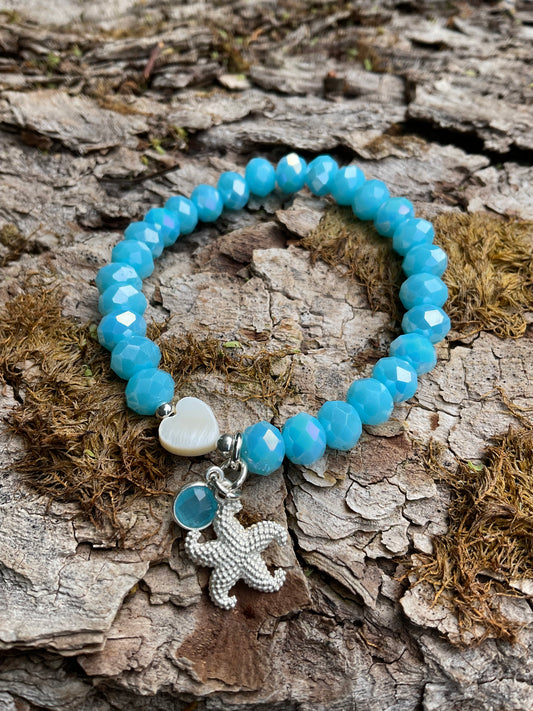 Ein blaues Armband mit einem Herz und einem silbernen Seestern Anhänger