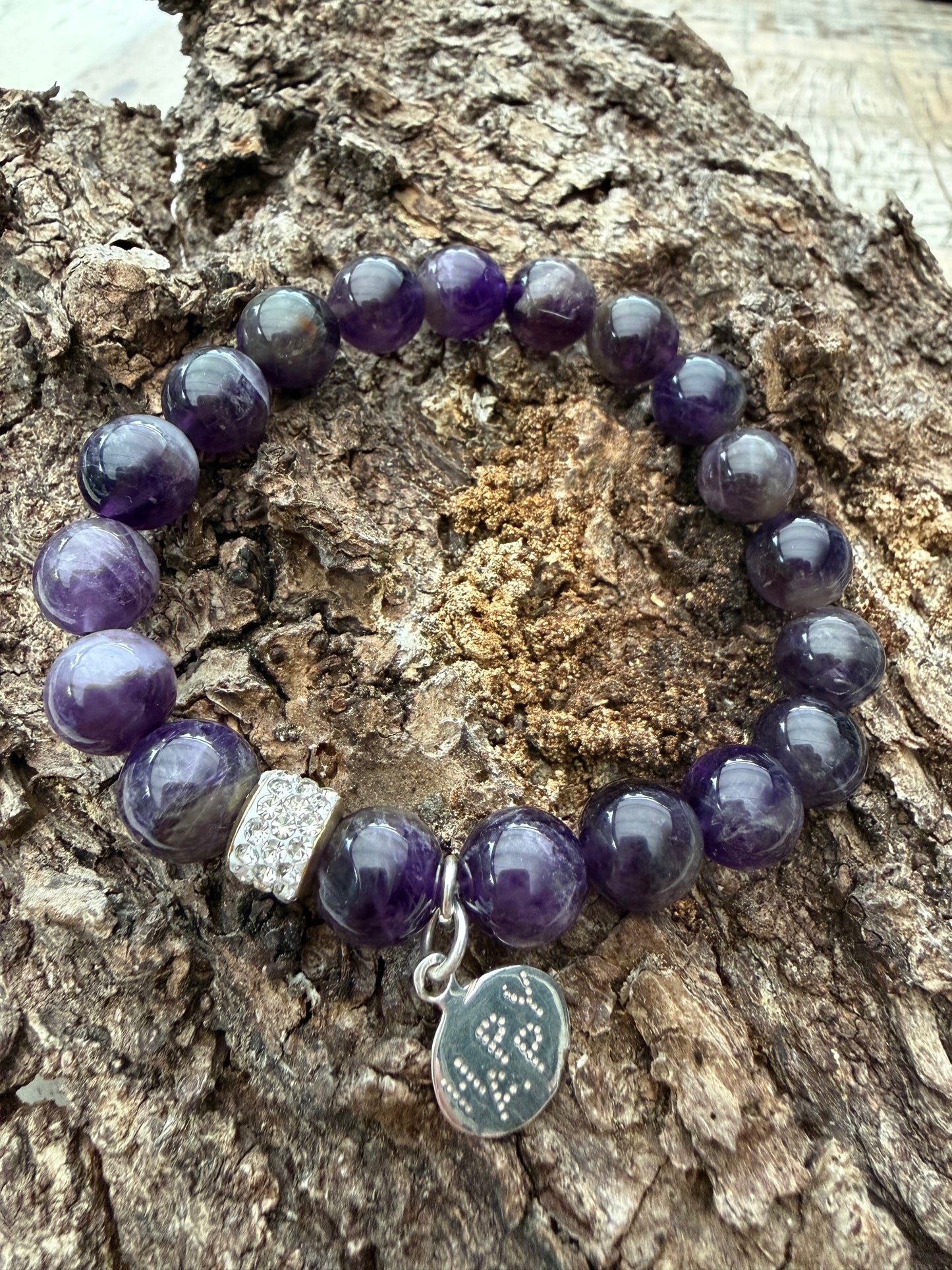 Ein violettes Perlenarmband mit happy Anhänger 