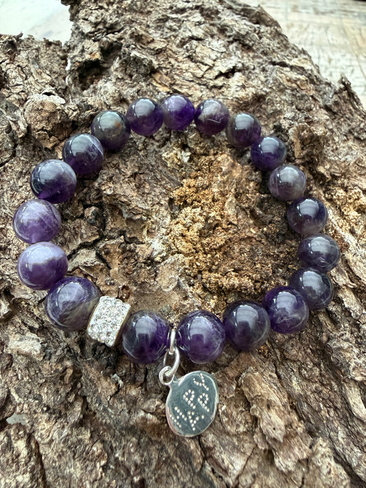Ein violettes Perlenarmband mit happy Anhänger 