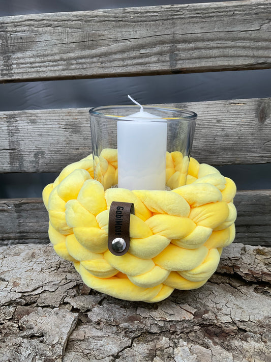 Ein gestricktes gelbes Windlicht mit Glaseinsatz 