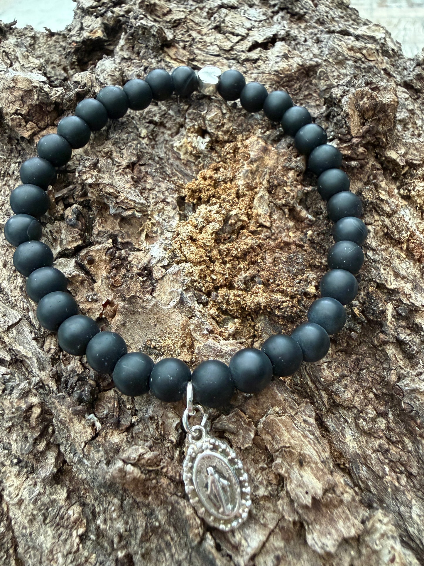 Ein schwarzes Perlenarmband mit Herz und Madonnen Anhänger 