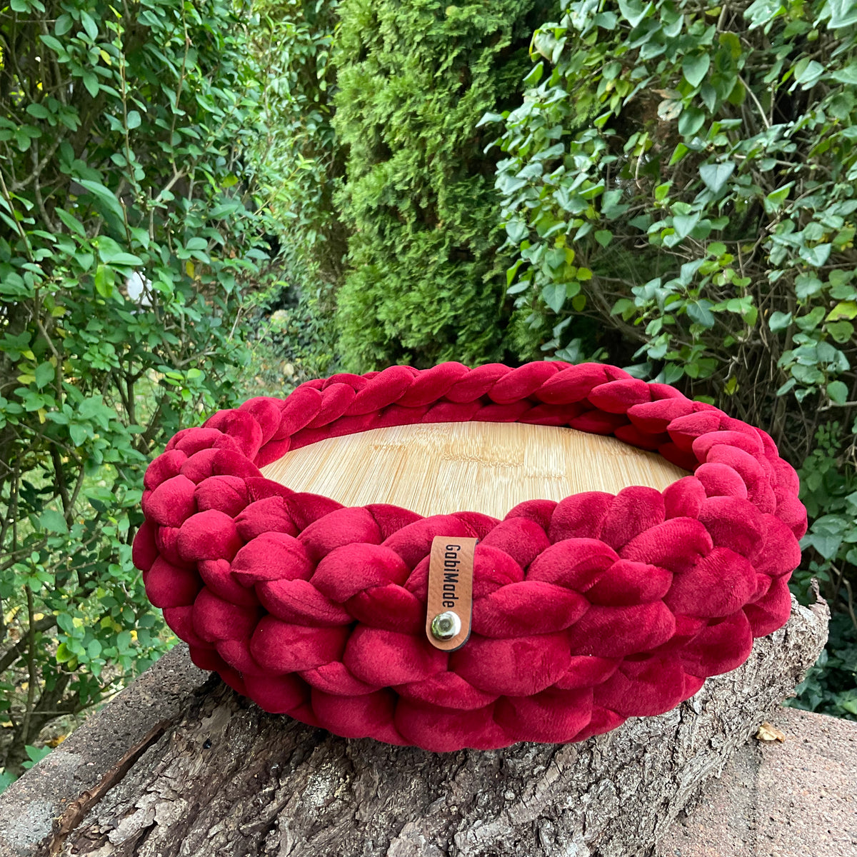 Ein gestricktes Tablett in Bordeaux mit Holzteller 
