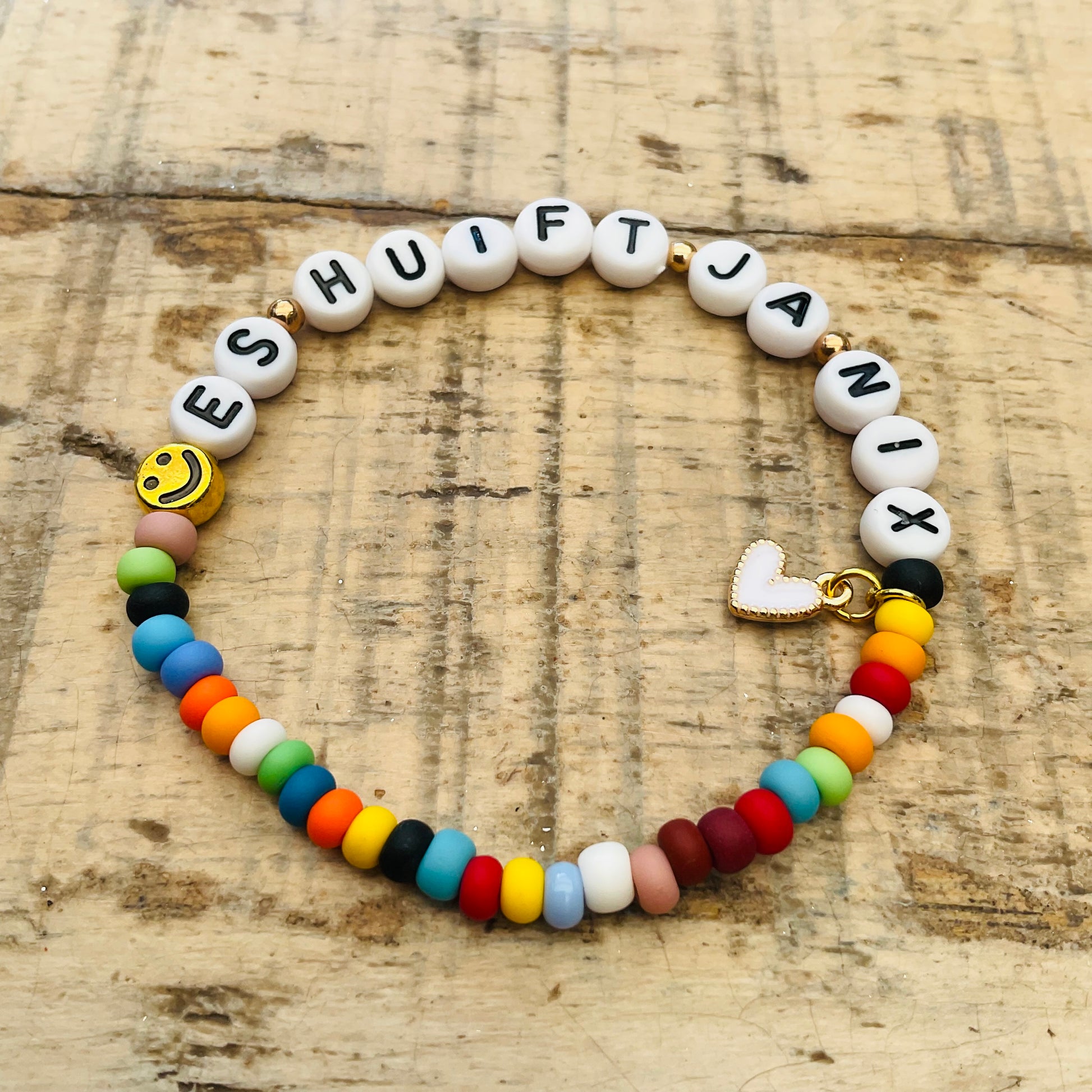 Ein buntes Armband mit ES HUIFT JA NIX und herzanhänger