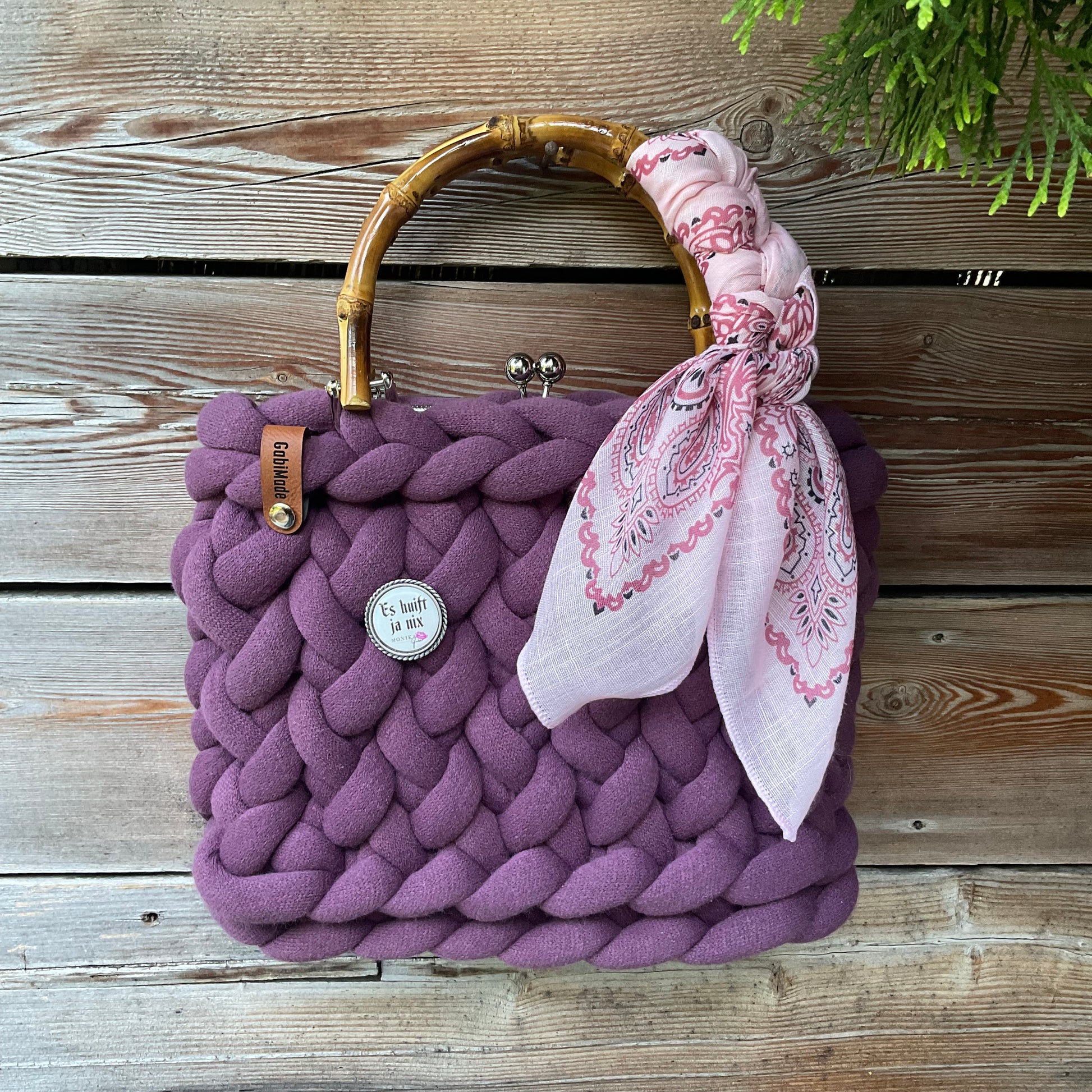 Eine violette Trachtentasche mit Tuch und Gaudiknopf 
