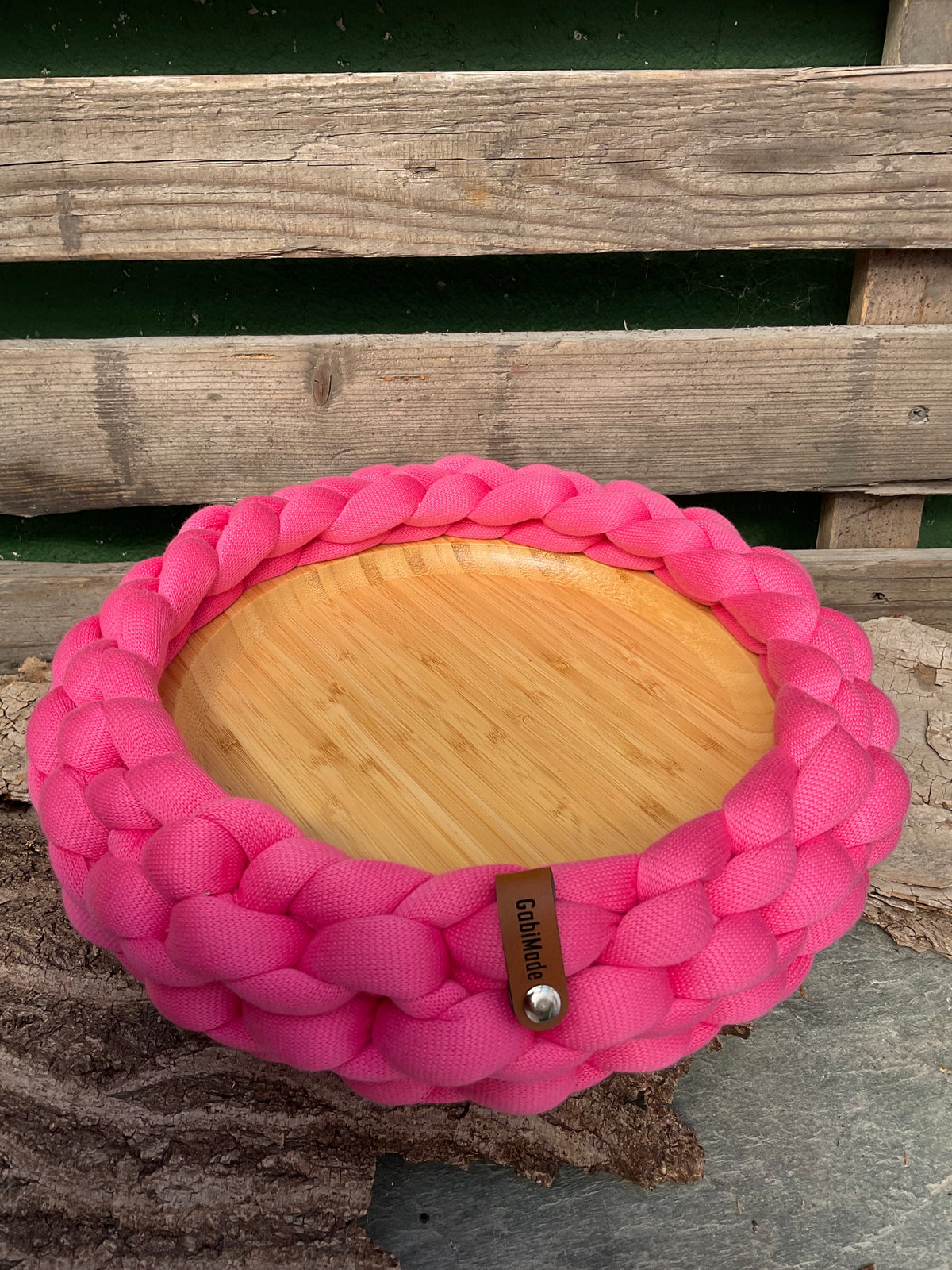 Ein gestricktes pinkes Tablett mit Holzteller 