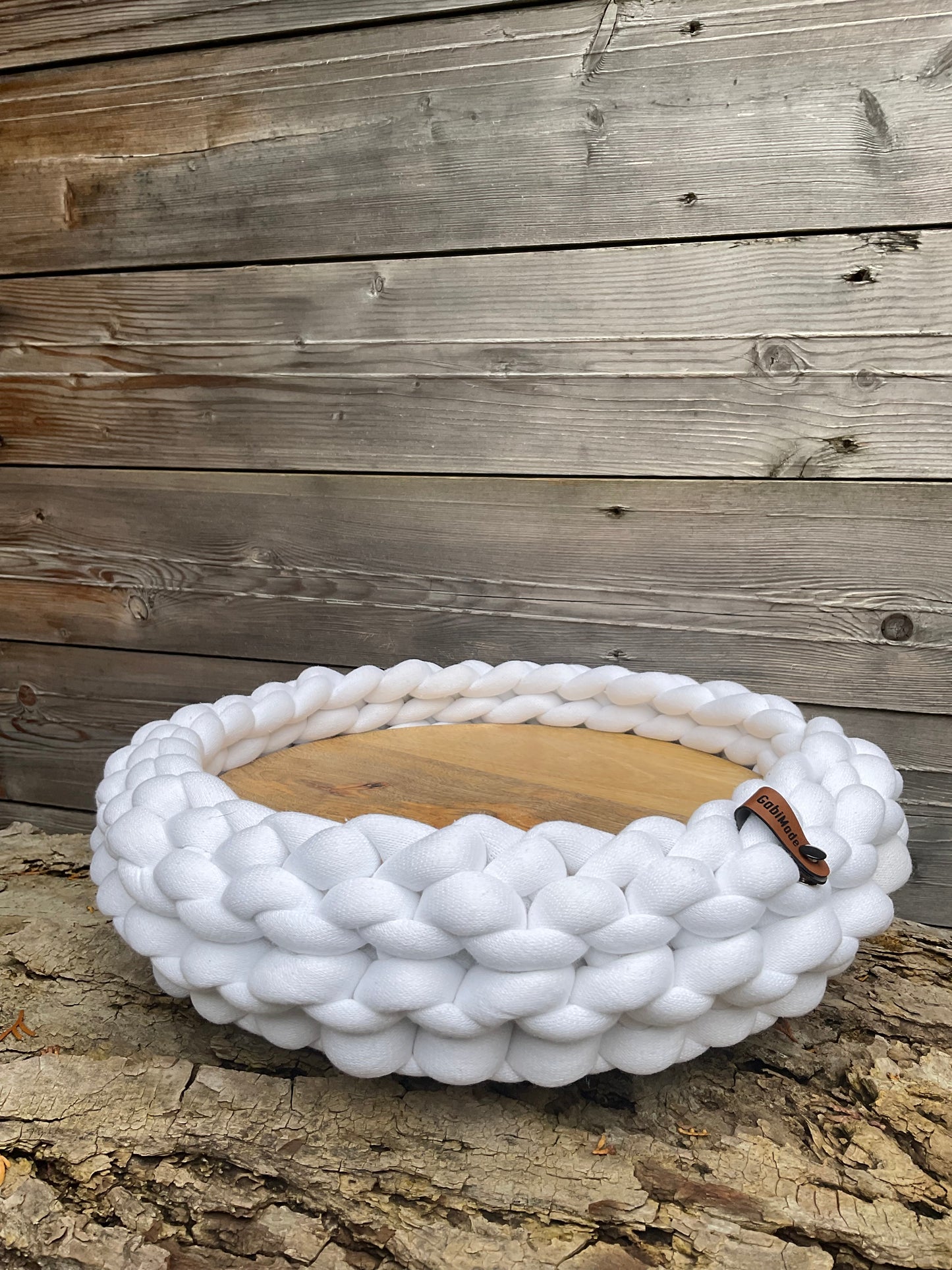 Ein gestricktes weißes Tablett mit Holzteller