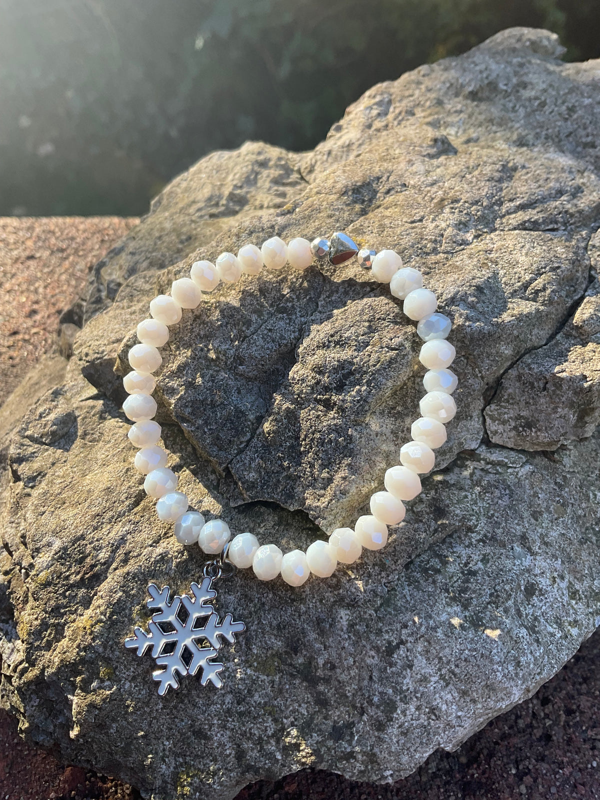 Ein weißes Armband mir einer emaillierten Schneeflocken Anhänger 