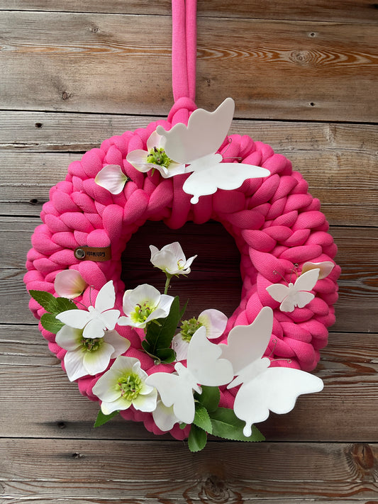 Ein pinker gestrickter geschmückter Kranz 