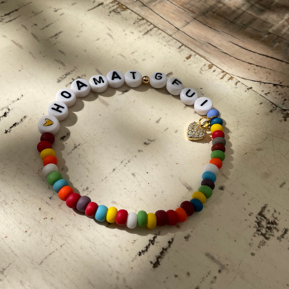 Ein buntes Perlenarmband mit glitzerndem Herzanhänger 