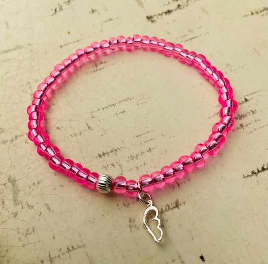 Ein pinkes Perlenarmband mit Flügelanhänger