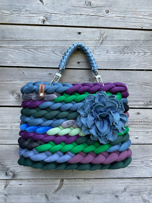 Eine mehrfarbige Tasche mit Ledergriffen und Blumenbrosche 