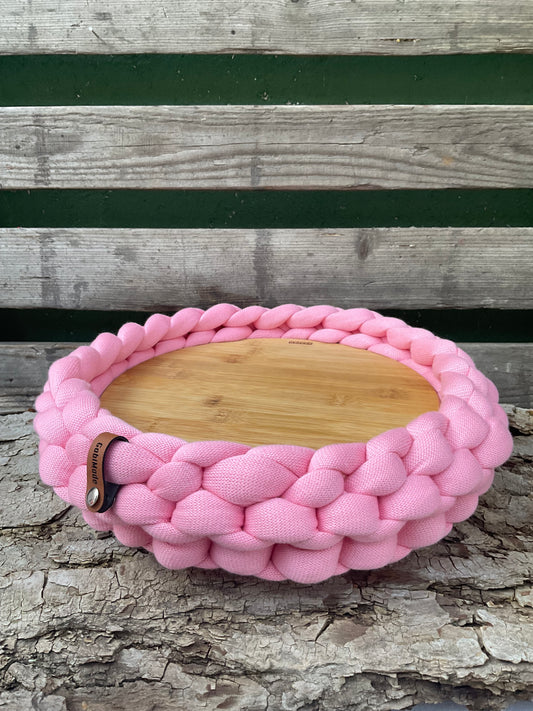 Ein gestricktes Tablett in rosa mit Holzteller 