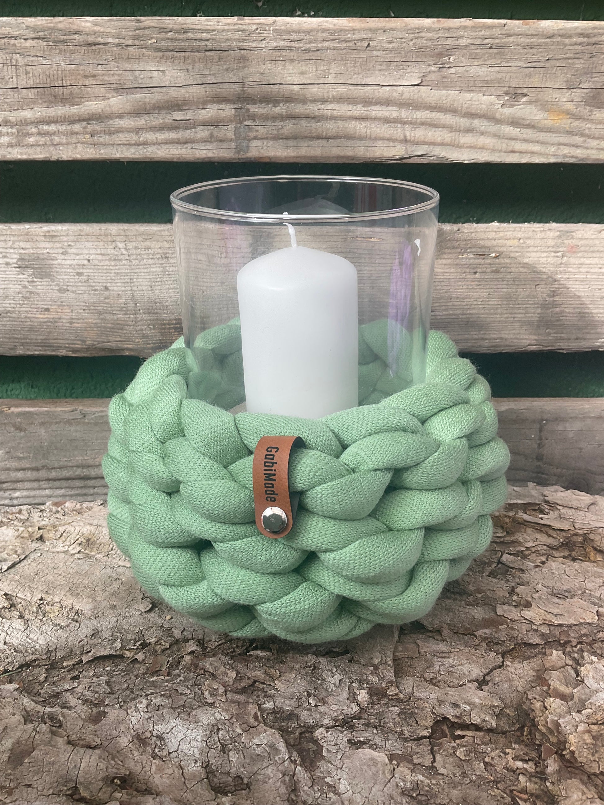Ein gestricktes grünes Windlicht mit Glaseinsatz