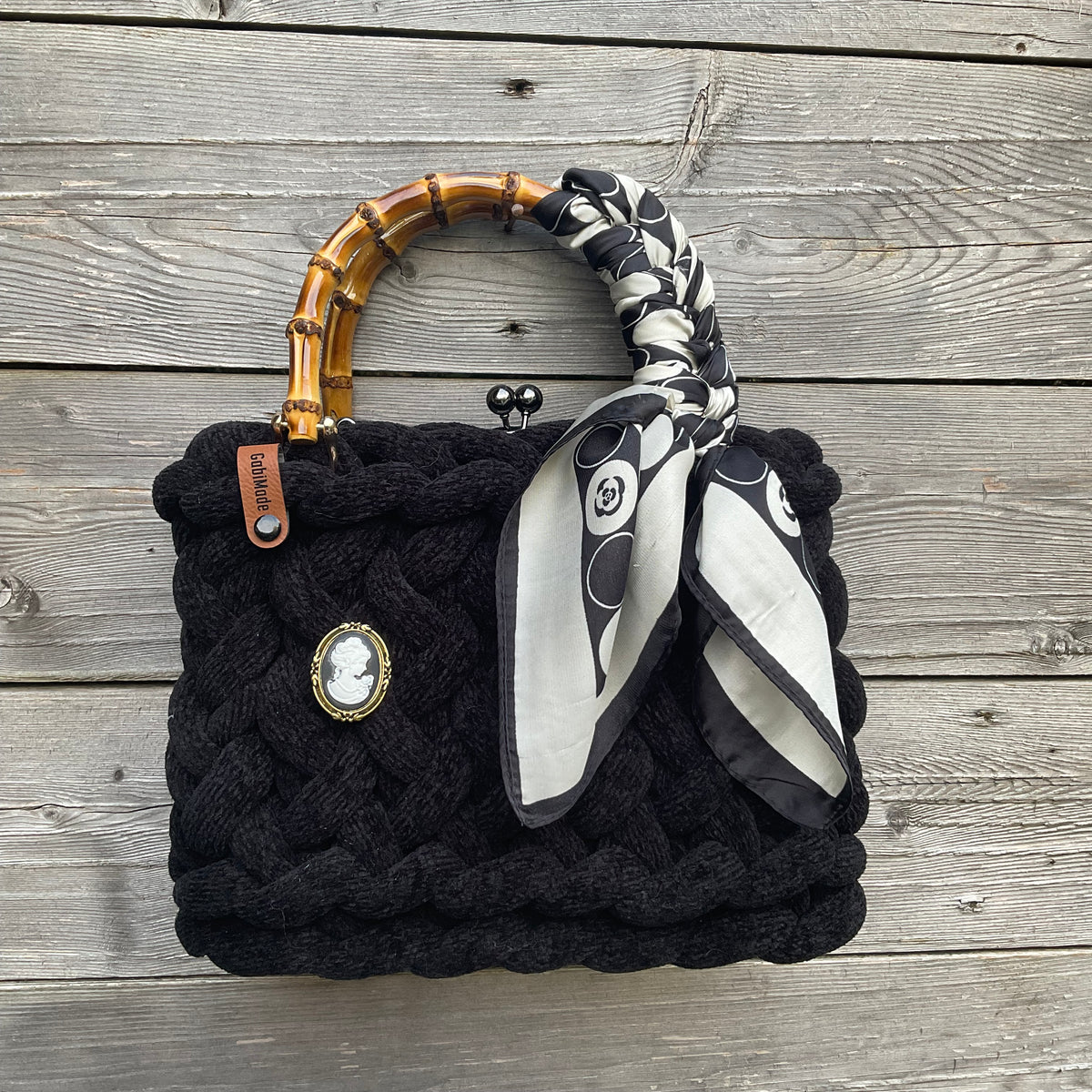 Eine gestrickte schwarze Trachtentasche mit Gemmenbrosche und Bambusgriffen 