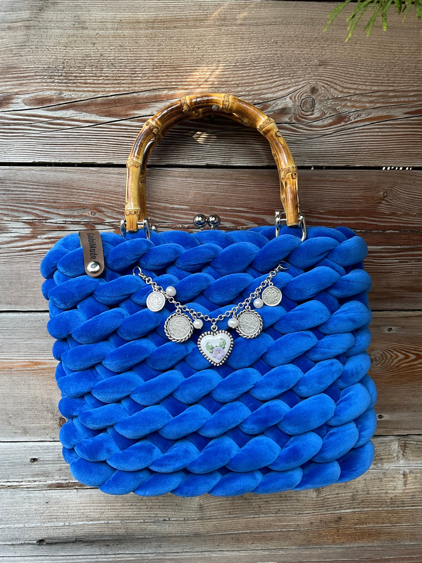 Eine gestrickte blaue Trachtentasche mit Bambusgriffen und charivari
