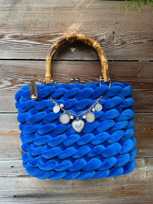 Eine gestrickte blaue Trachtentasche mit Bambusgriffen und charivari