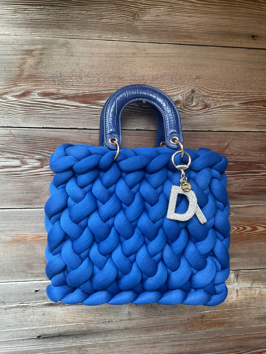 Eine gestrickte blaue Tasche mit passenden Henkeln