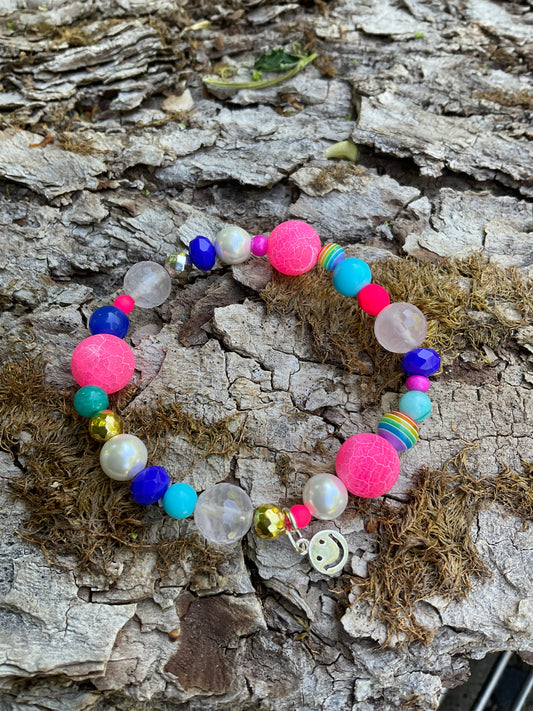 Ein buntes Armband mit einem silbernen Smiley Anhänger
