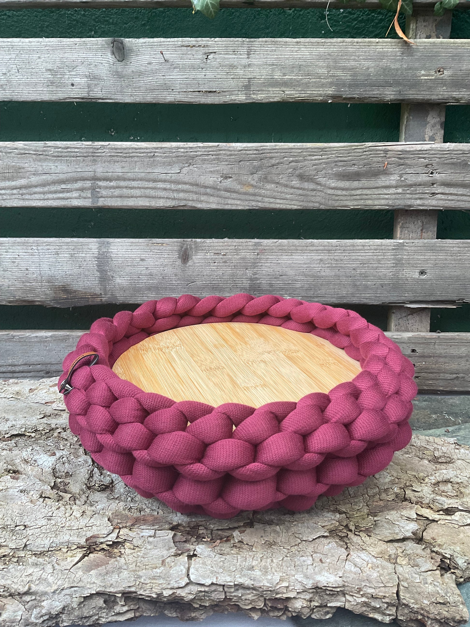 Ein gestricktes Tablett in Bordeaux mit holzteller