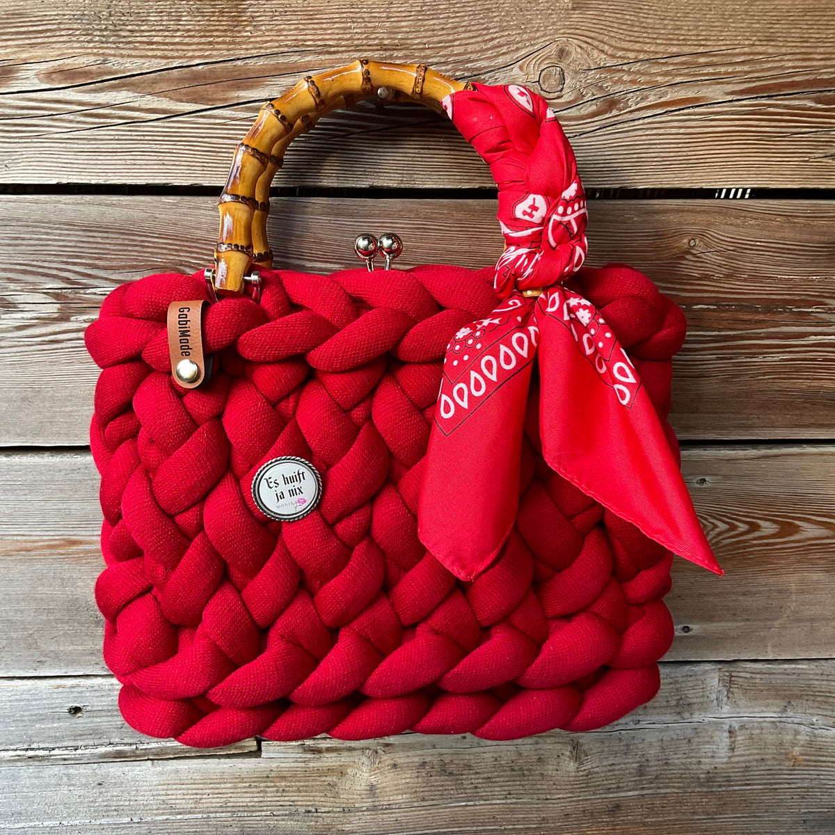 Eine gestrickte rote Tasche mit Tuch und Gaudiknopf 