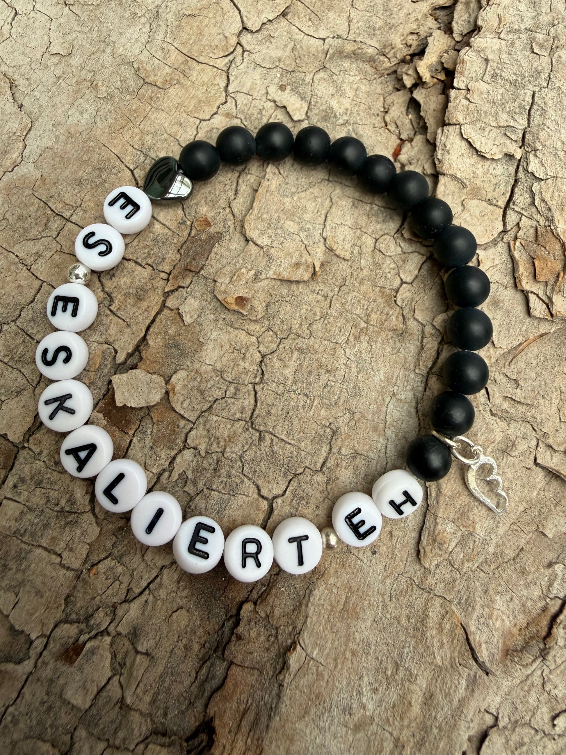 Ein schwarzes petlenarmband mit Flügelanhänger