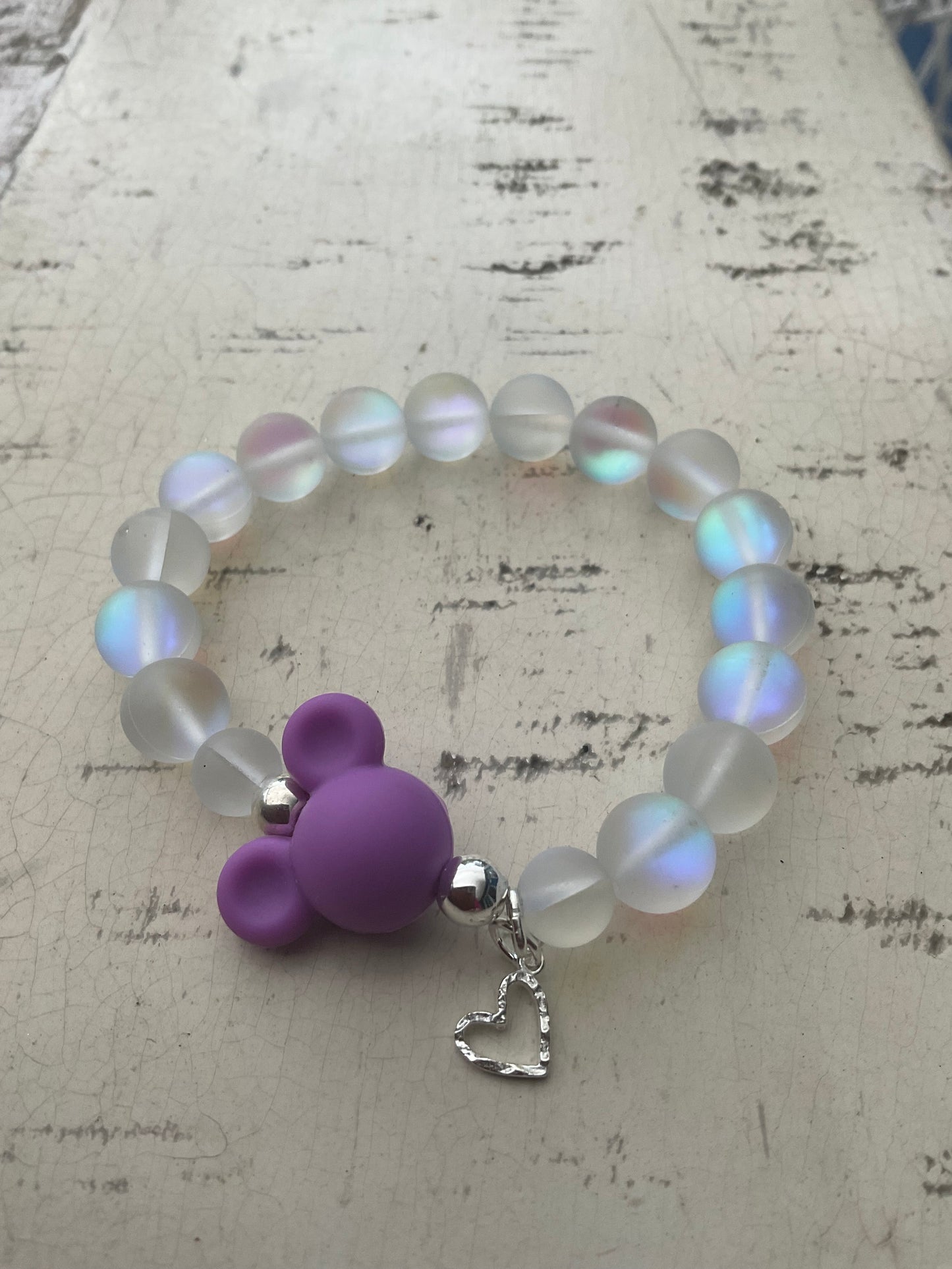 Ein schimmerndes Perlenarmband mit lila MausiKopf