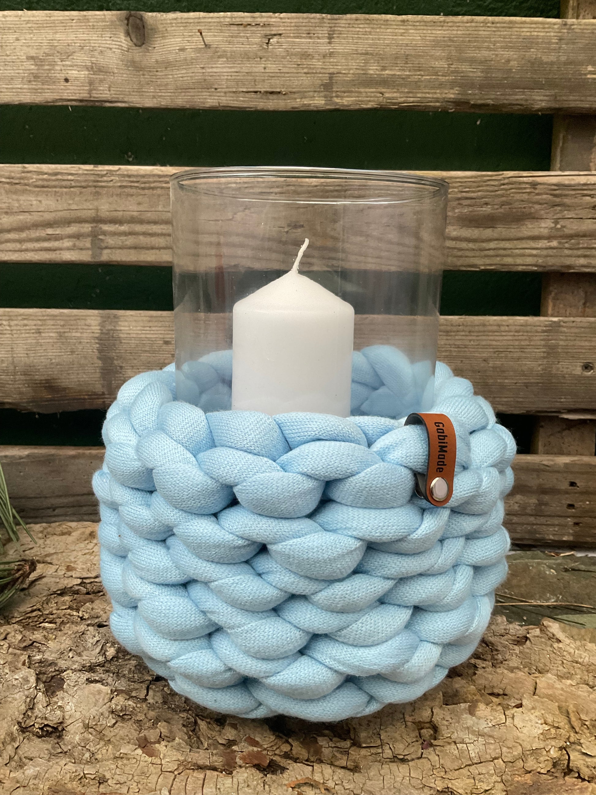 Ein gestricktes hellblaues Windlicht mit Glaseinsatz 