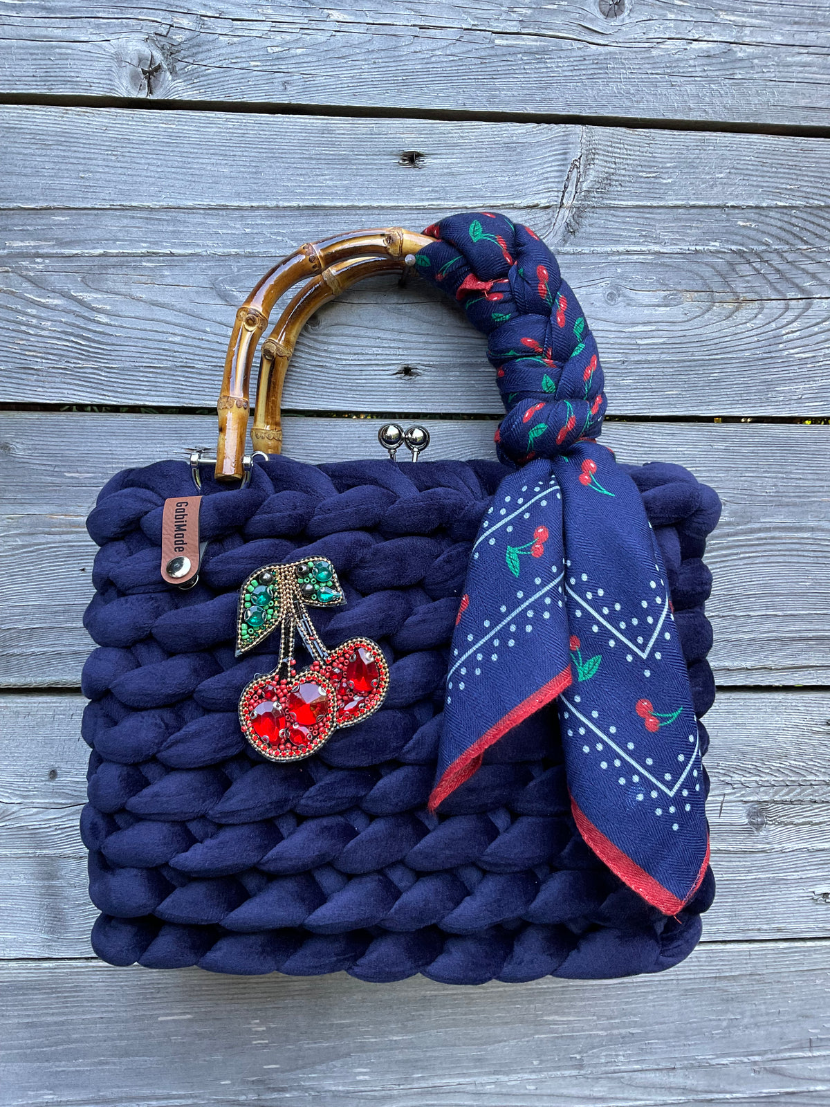 Eine gestrickte blaue Trachtentasche mit Brosche und Bambusgriffen