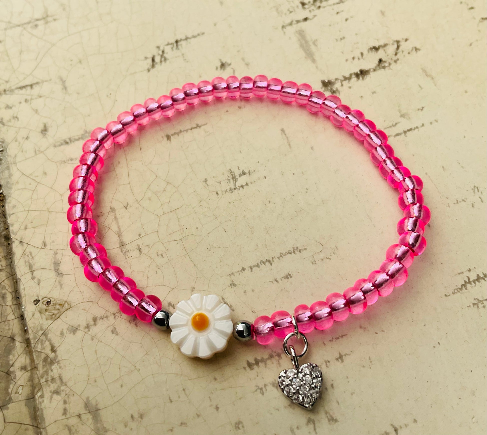 Ein pinkes Perlenarmband mir Glitzer Herzanhänger 