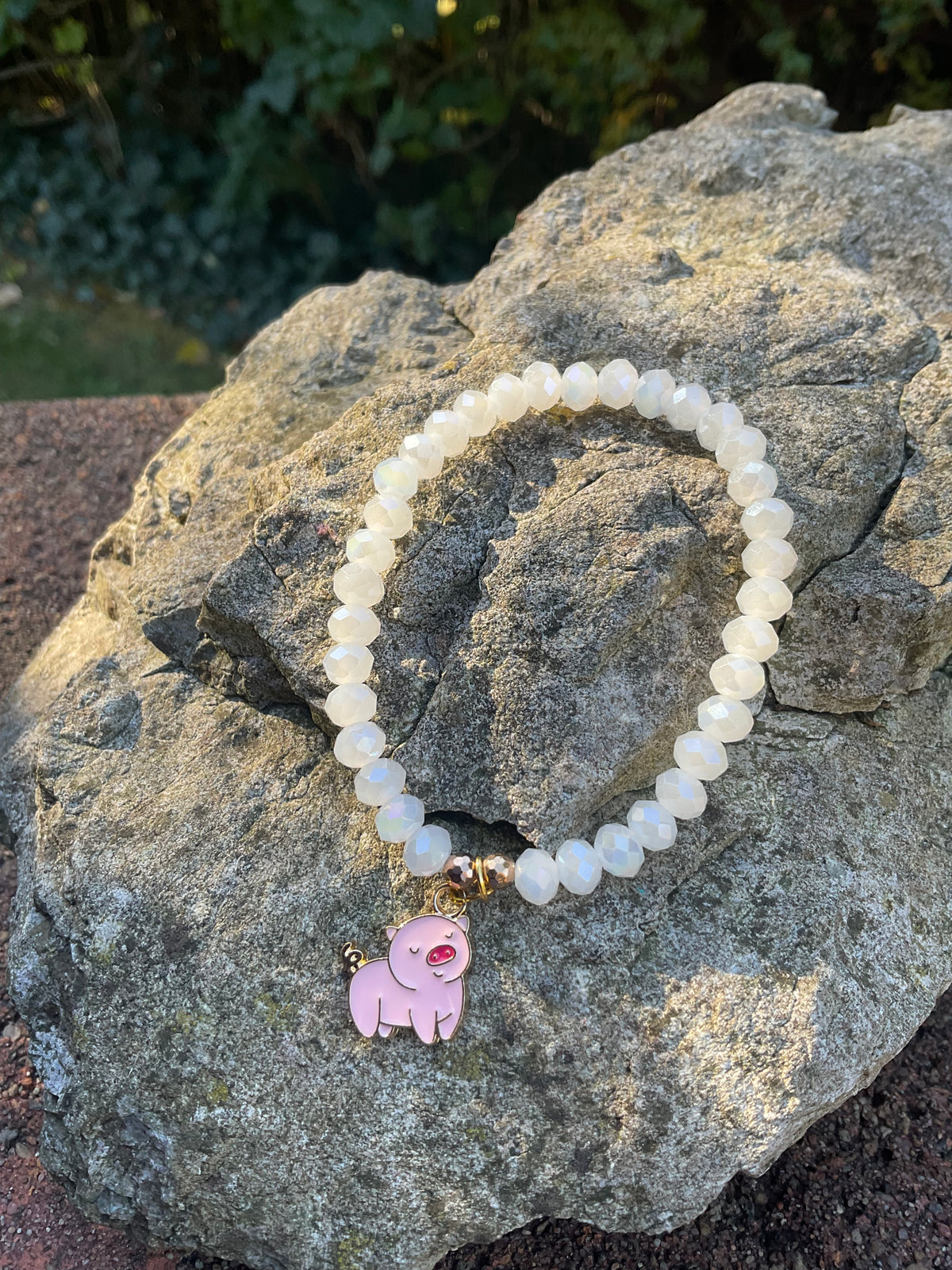 Ein weißes Perlenarmband mit Schweinchen Anhänger 