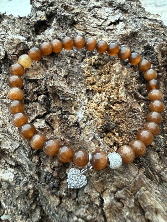 Ein braunes Perlenarmband mit Silberperle und Herzanhänger 