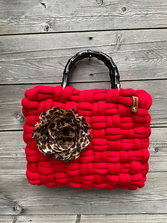 Eine rote gestrickte Tasche mit Blumenbrosche 