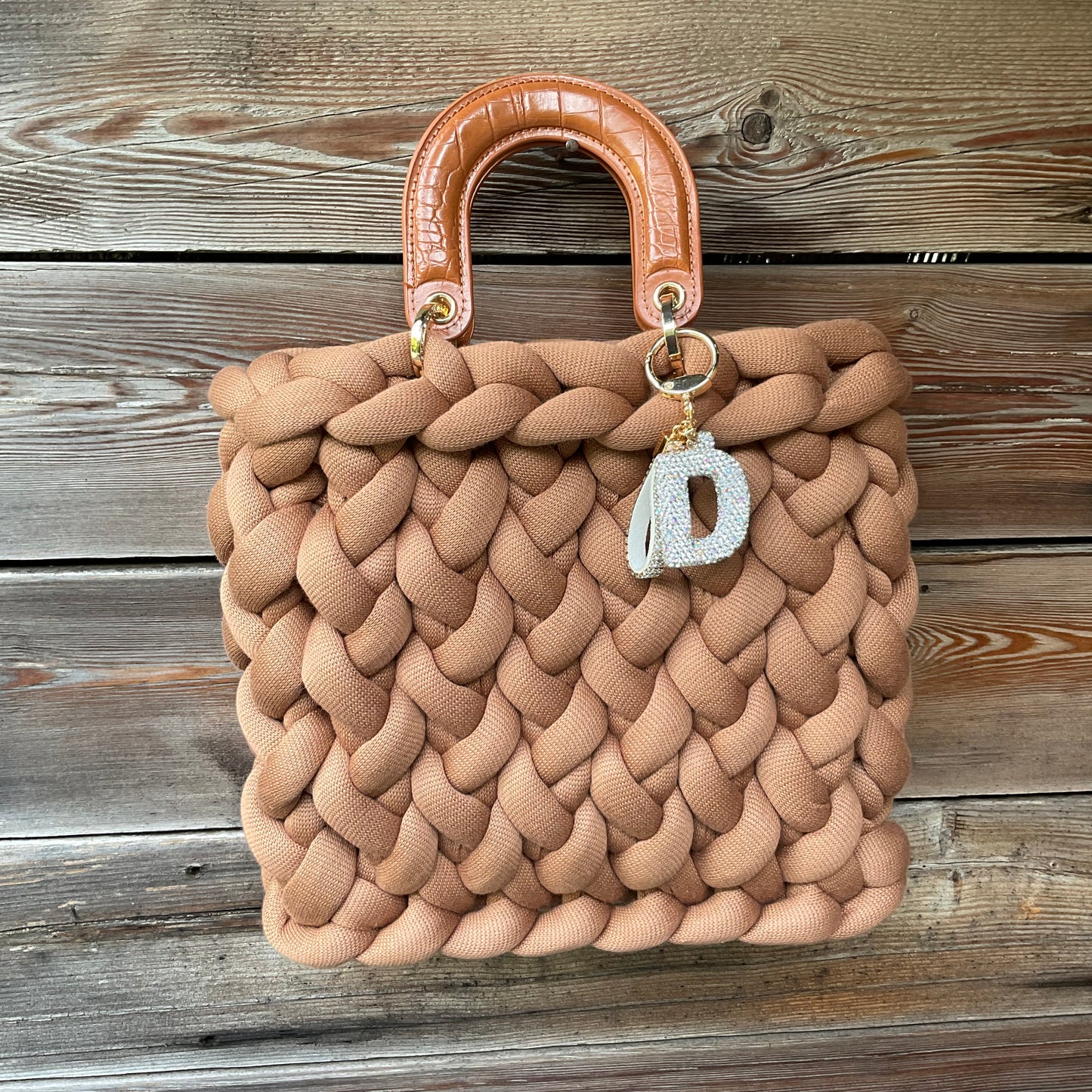 Eine gestrickte cognacfarbene Tasche mit Anhänger und Henkel 