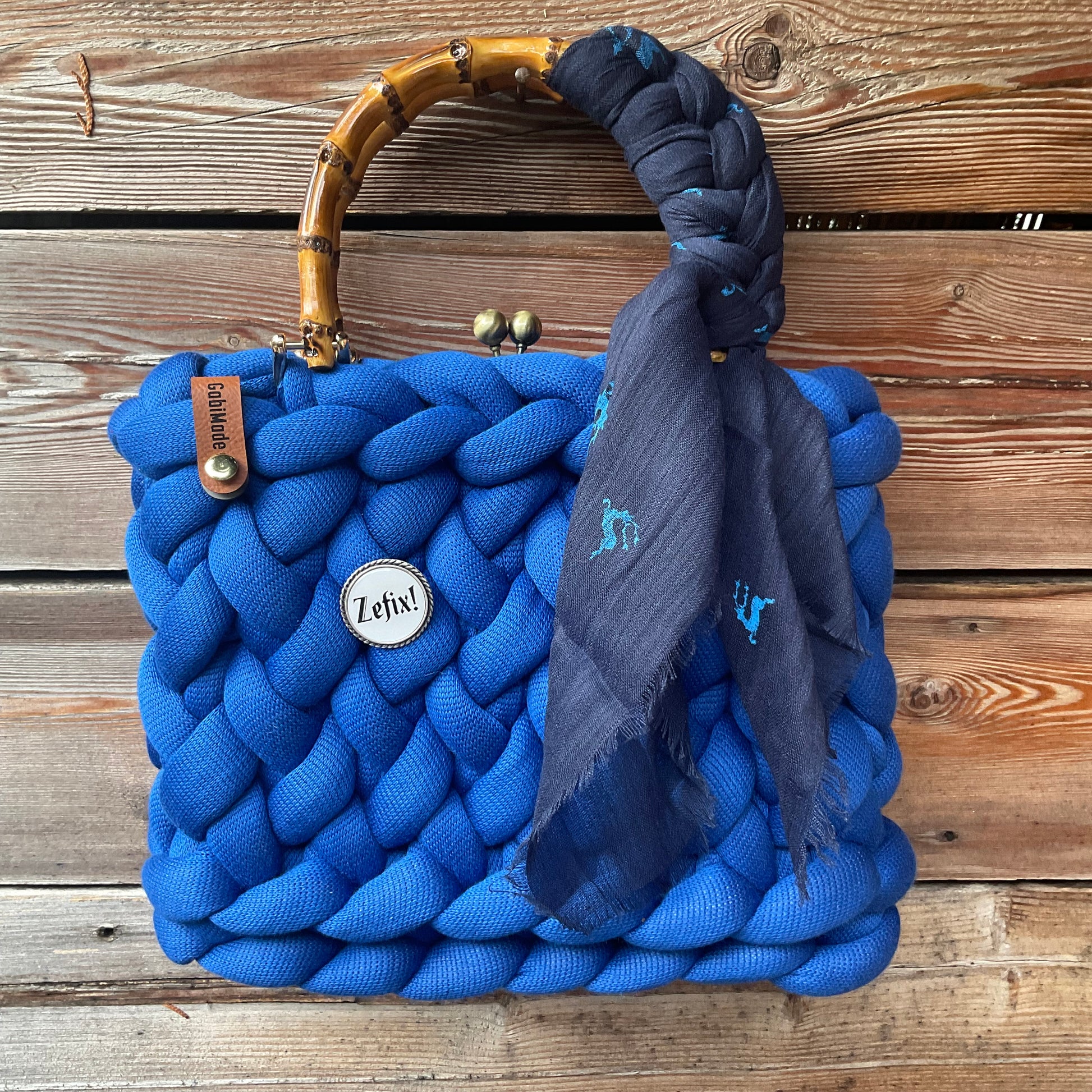 Eine blaue Trachtentasche mit Gaudiknopf und Tuch 