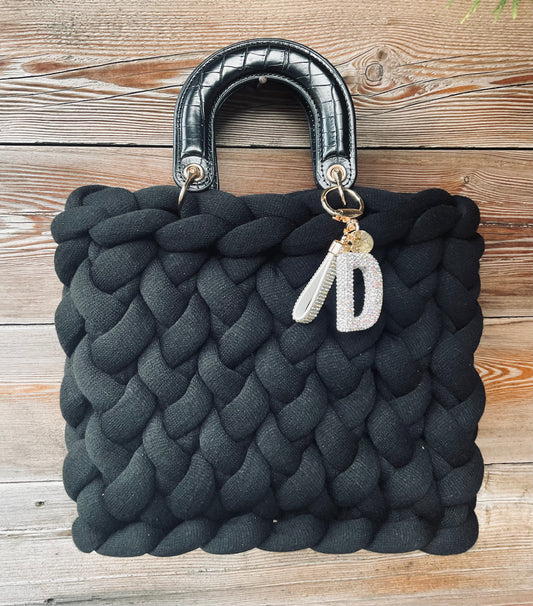 Eine schwarze gestrickte Tasche mit Henkel 