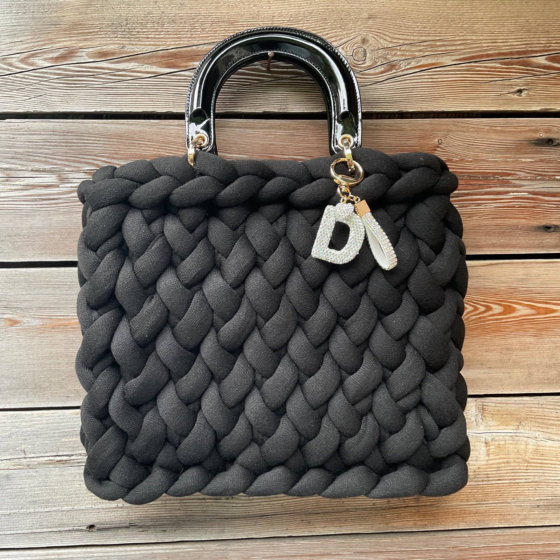 Eine gestrickte schwarze Tasche mit Anhänger und Henkel 