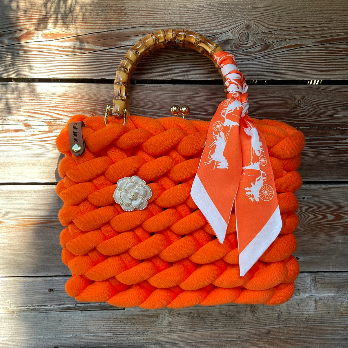 Eine gestrickte orange Trachtentasche mit Twilly uns d Bambusgriffen 