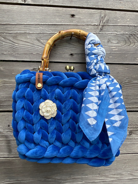 Eine blaue gestrickte Tasche mit Griffen und Tuch