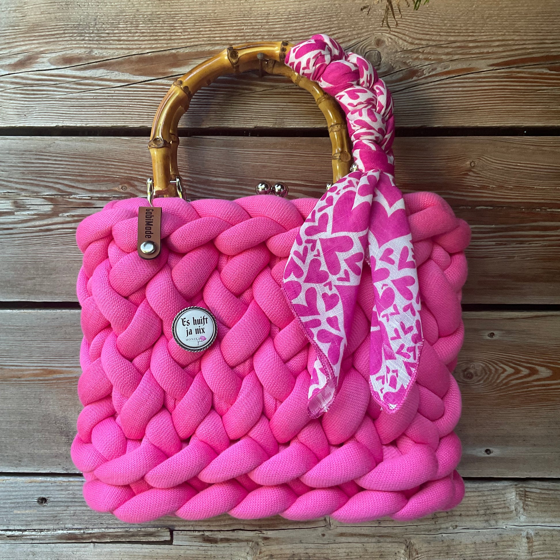 Eine pinke Trachtentasche mit Gaudiknopf und Tuch  