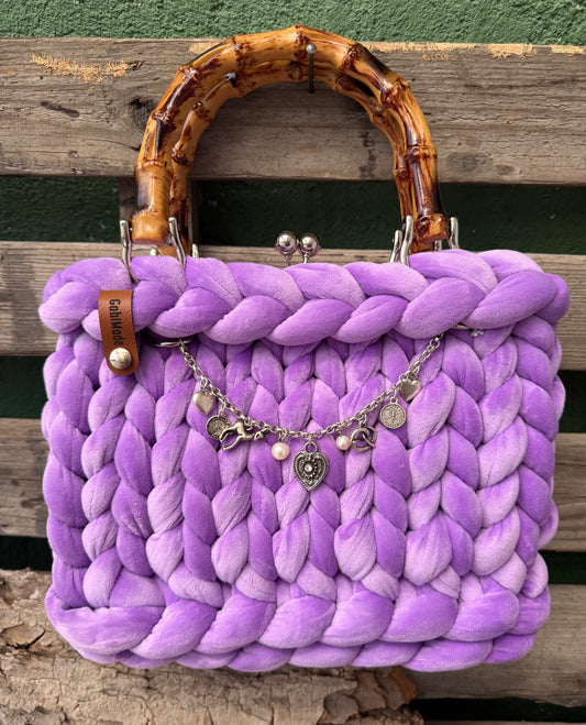 Eine gestrickte lila Trachtentasche mit Charivari und Bambusgriffen 
