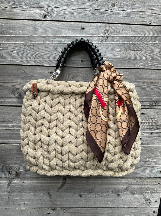 Eine gestrickte Tasche in beige mit Ledergriffen 