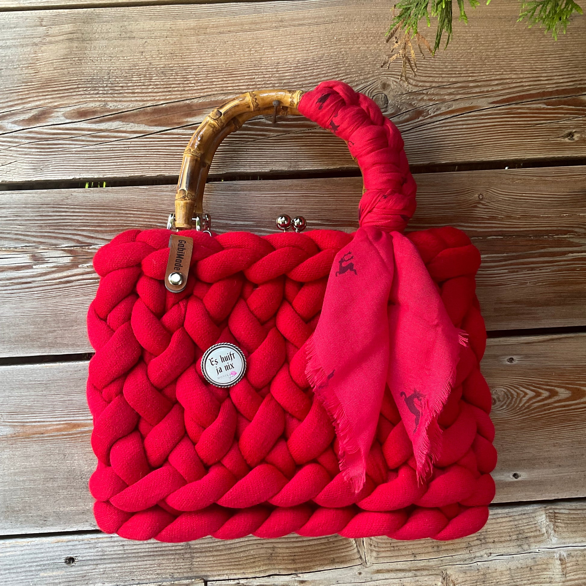 Eine rote Trachtentasche mit Gaudiknopf und Tuch 