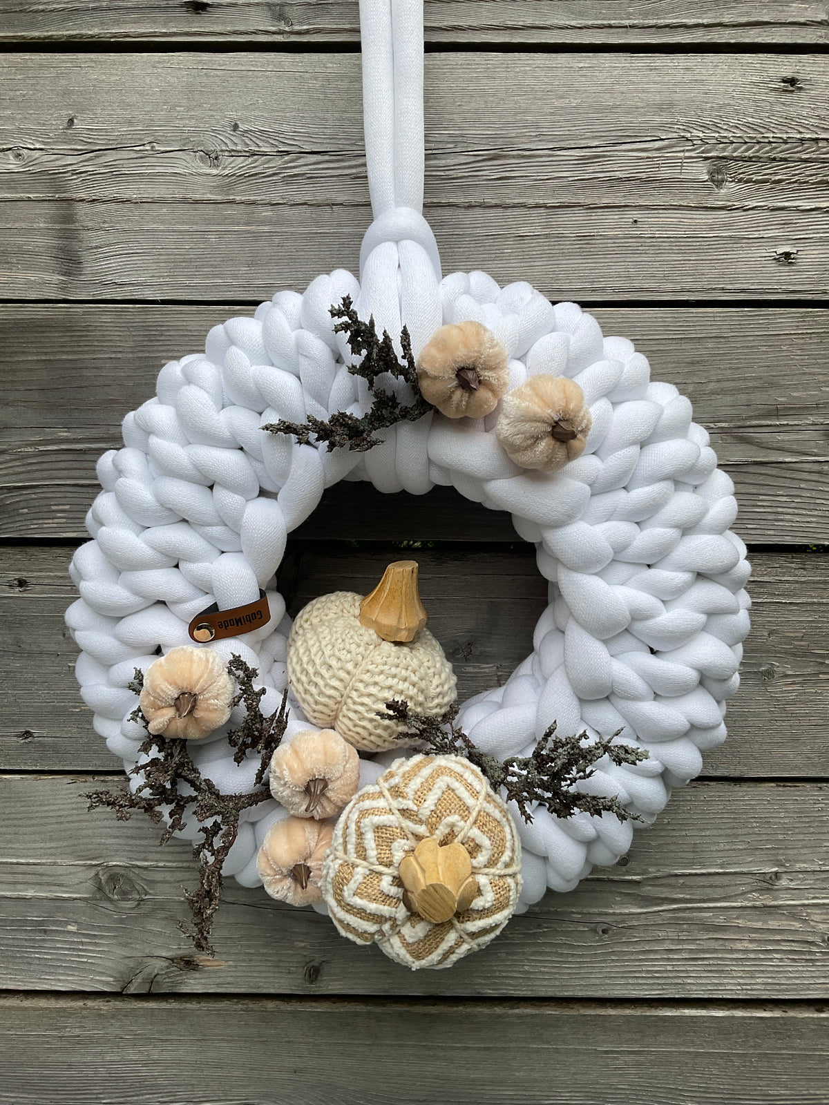 Ein gestrickter weißer Kranz mit herbstdekoration 