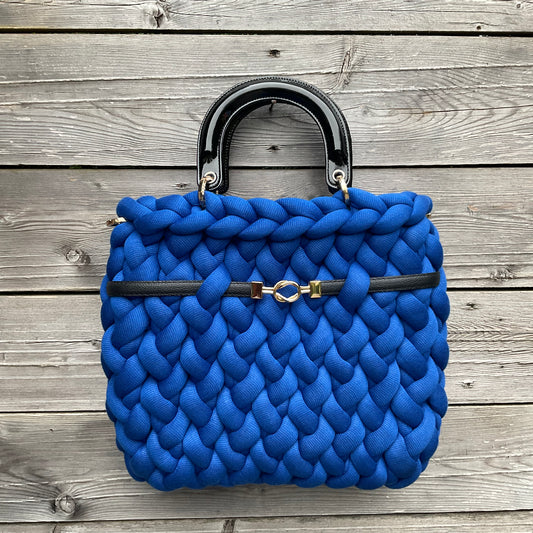 Eine gestrickte blaue Tasche mit Henkeln und Ziergurt