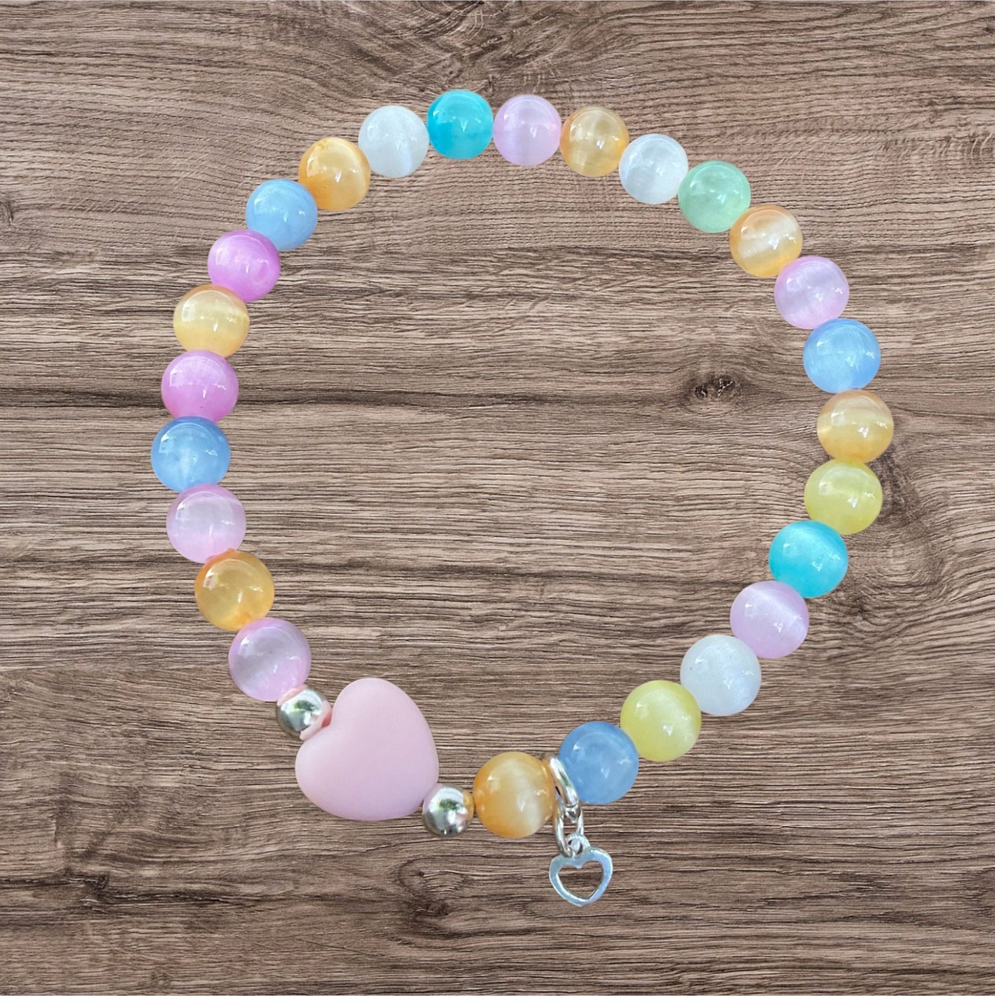 Ein buntes Armband mit einer Rosa Herzperle und einem silbernen Herzanhänger