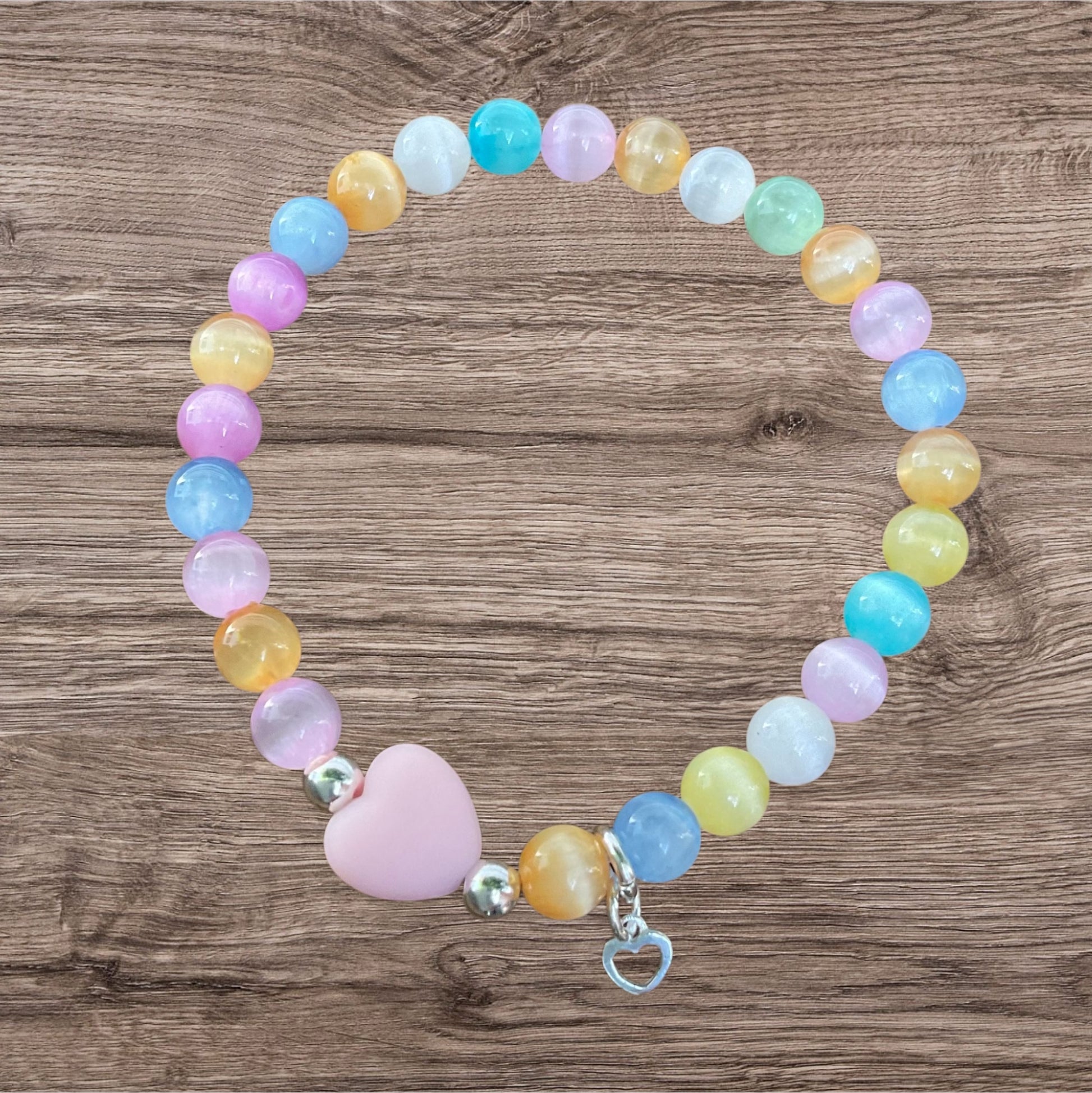 Ein buntes Armband mit einer Rosa Herzperle und einem silbernen Herzanhänger